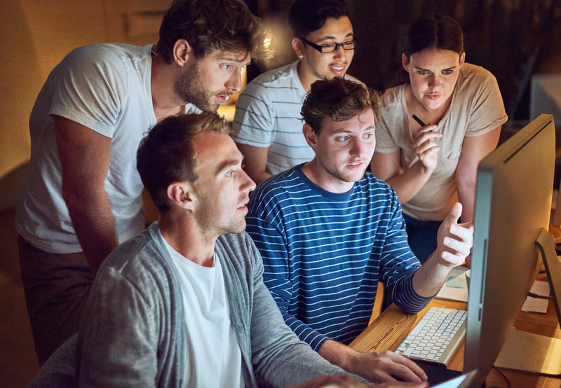 Teamwork beim Website Testing mehrere Leute schauen auf einen Bildschirm Stockimage
